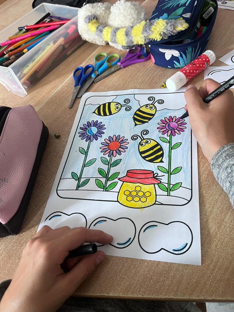 Dziecko koloruje obrazek z pszczołami